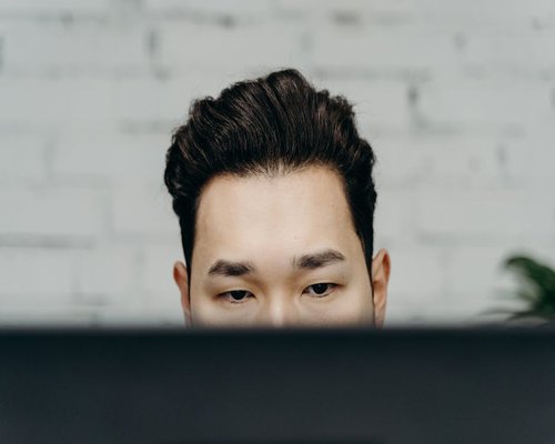 Man looking away from his computer screen to rest his eyes